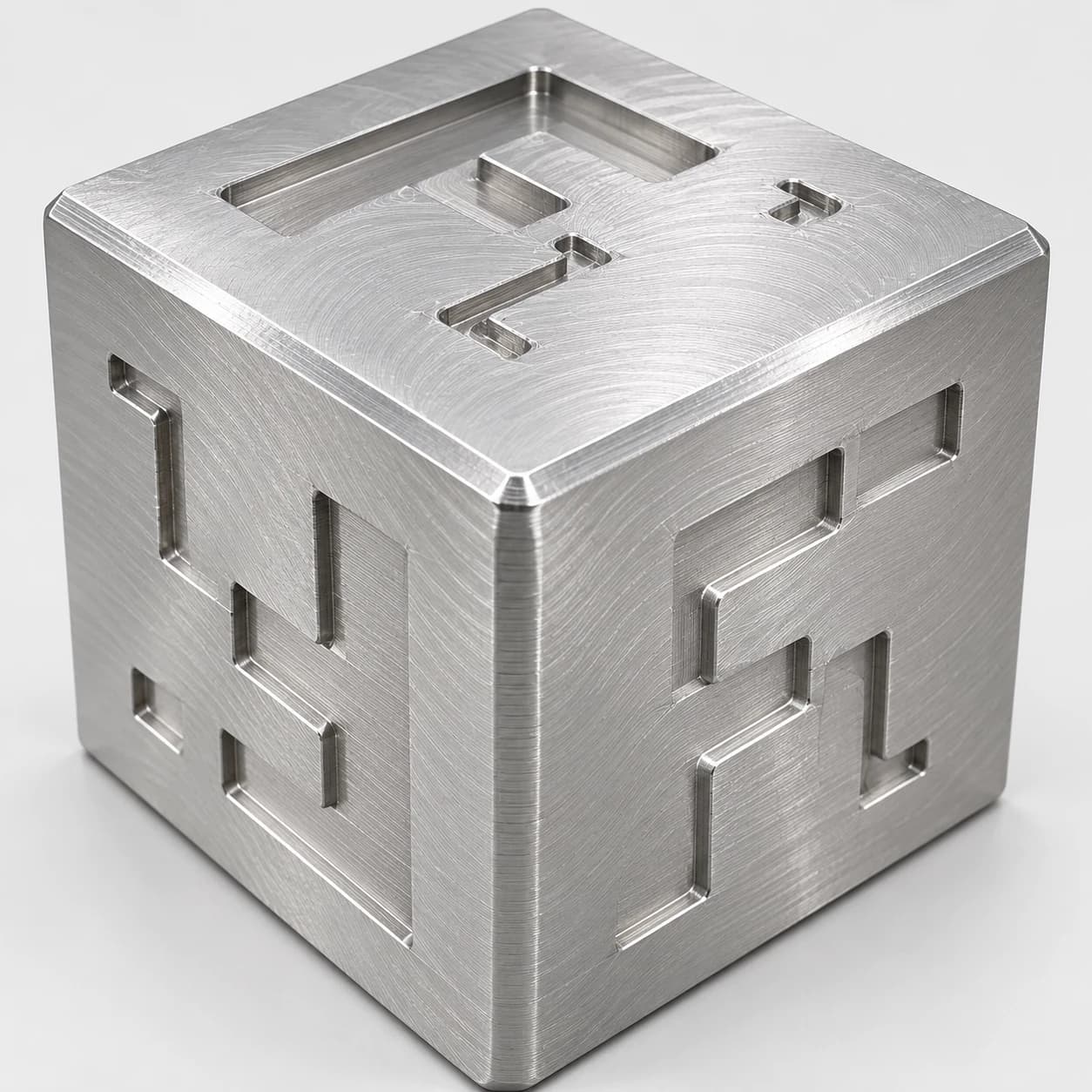 Forge Labs CNC sample cube with machined pockets and chamfered edges, shown in metal