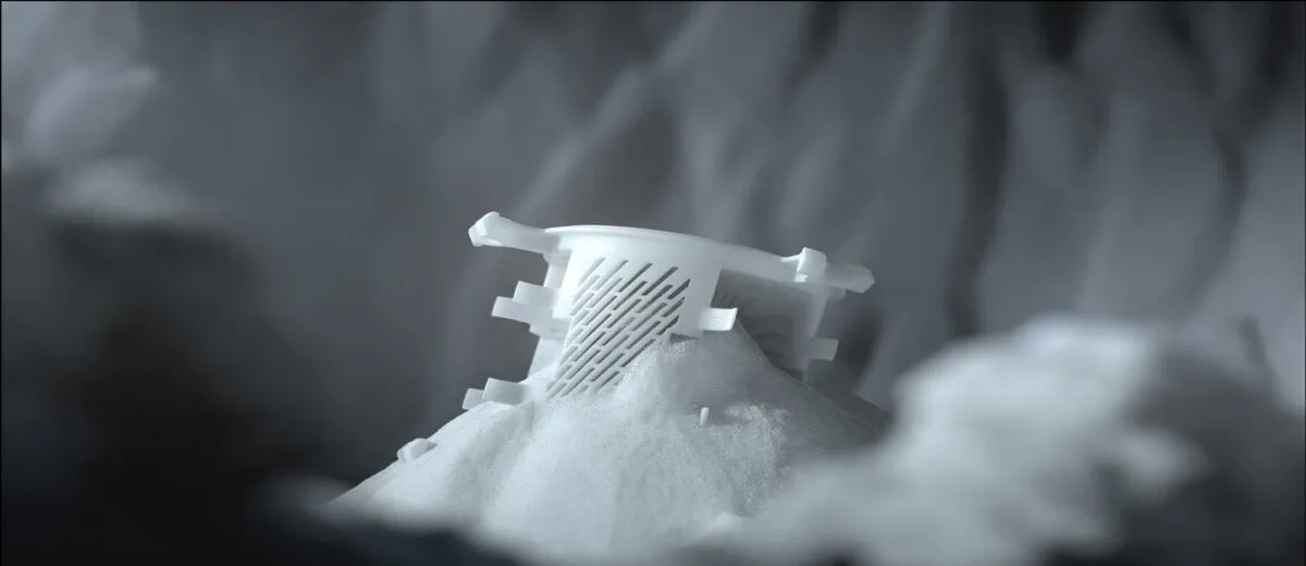 White SLS nylon part emerging from unsintered powder