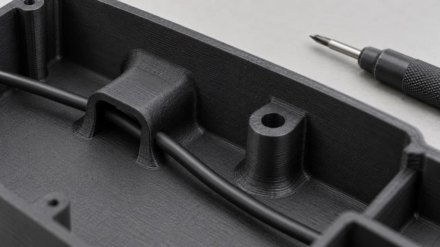 Close view of a cable guide and mounting lug inside a matte black printed electronics enclosure